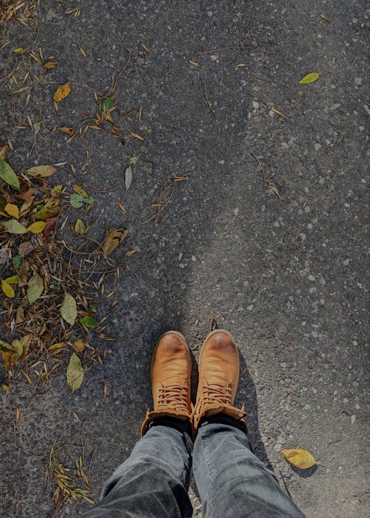 Close-up of a man's brown leather boots on outdoor ground, illustrating practical footwear for garden use